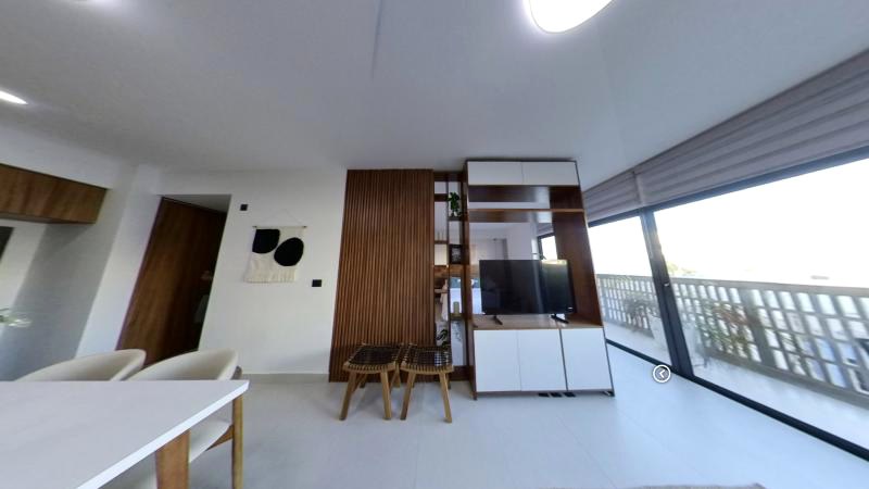 Sala del departamento muestra de Quartier, con muro de madera y la terraza con celosía al fondo